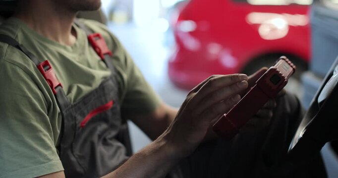 Close up work process in the maintenance center. Mechanic is using modern technologies in the workshop. Automotive industry, auto care, service.