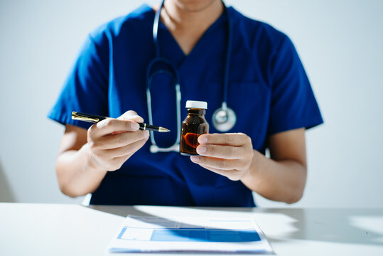 A professional scientist in a lab coat inspecting blue and white medical capsules on a petri dish. Concept of pharmaceutical research, health care development