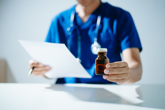 A professional scientist in a lab coat inspecting blue and white medical capsules on a petri dish. Concept of pharmaceutical research, health care development