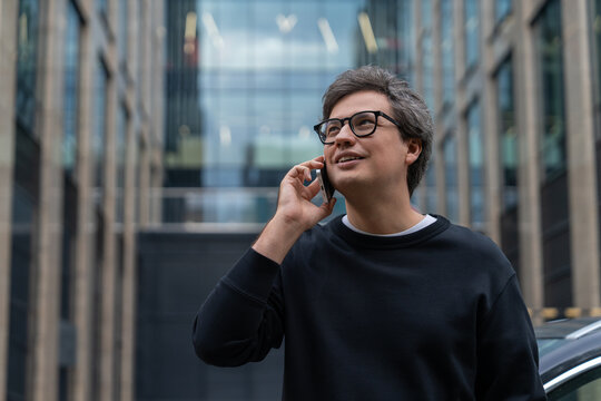 Businessman talking on smartphone in modern city street, confide