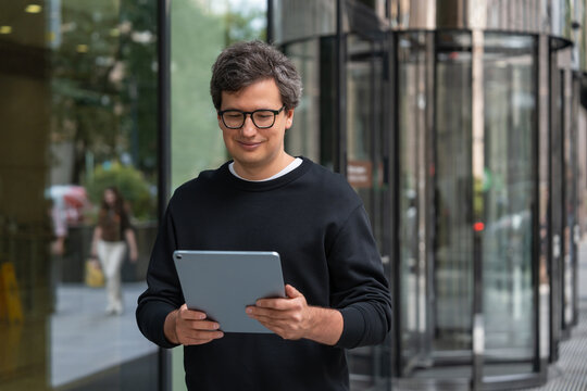 Confident businessman using a tablet outside a modern office bui