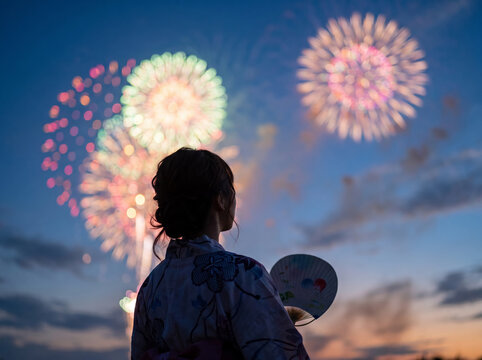 夜空に広がる大輪の打ち上げ花火を眺める浴衣姿の女性