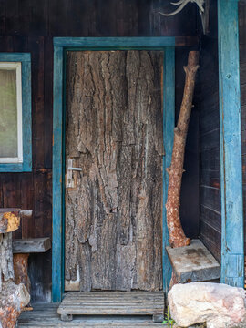 Rustic Bark Covered Door With Blue Trim On Cabin Porch