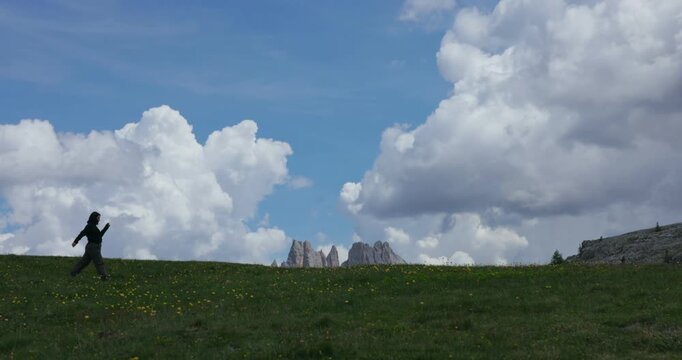 Woman enjoying the scenic landscape at Cinque Torri near Cortina d'Ampezzo in the Dolomites, Veneto, Italy - wide shot