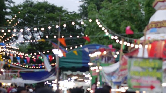 Blurred Crowd at Thai Night Market with Bokeh String Lights and Colorful Flags