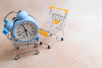 Mini shopping cart holds clock while empty cart waits beside it on a neutral background © ir1ska