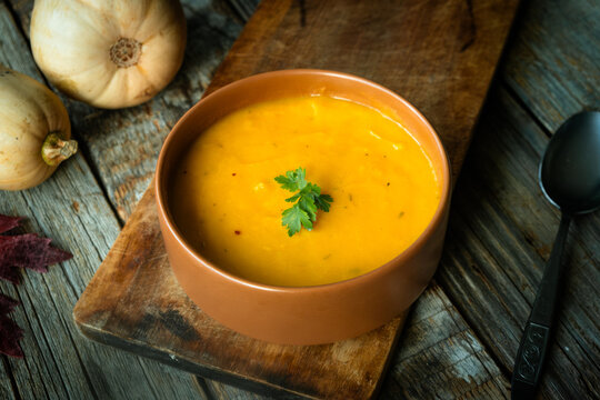 Creamy pumpkin soup topped with a parsley sprig. Thanksgiving meal.