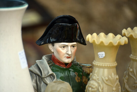 Bust statue of Napoleon displayed among various vintage objects at a flea market, illustrating French history, antique collecting and second hand market culture.
