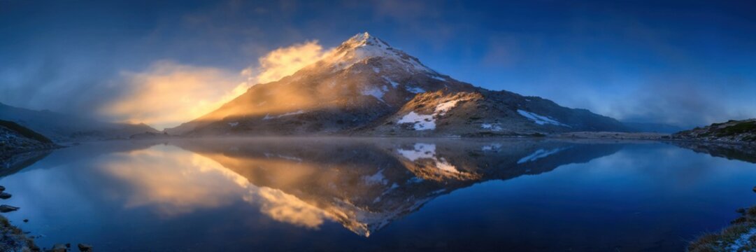 Majestic Mountain Peak Reflecting in a Serene Lake at Sunrise.