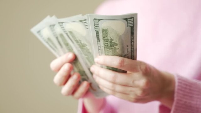 Close up of woman hands counting a stack of US dollar banknotes. Female calculate saving, income, cash payments. Investment planning and personal money management.