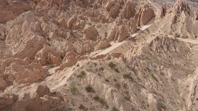 Rugged sandstone ridges of Quebrada de las Flechas beneath cloudy mountain sky, aerial panoramic establishing backdrop, Salta Region Argentina