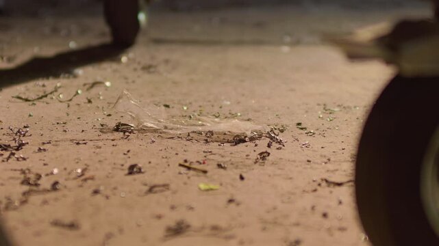 Metal shavings lathe turnings on workshop floor under sunlight, handheld close up shot. Industrial steel scrap pile illuminated by warm daylight inside garage.