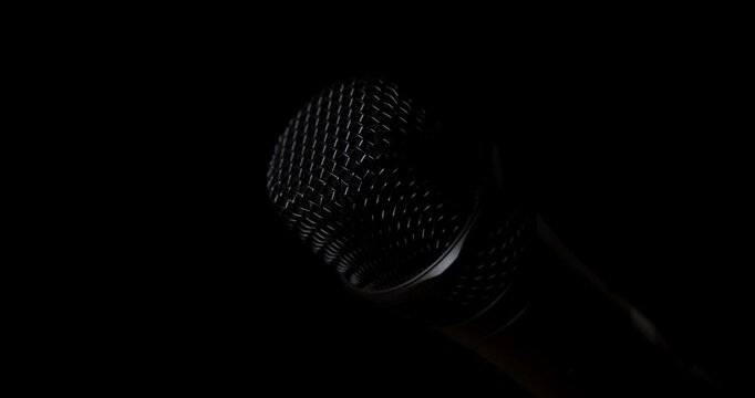 Cinematic light sweeping across microphone on black background, loop