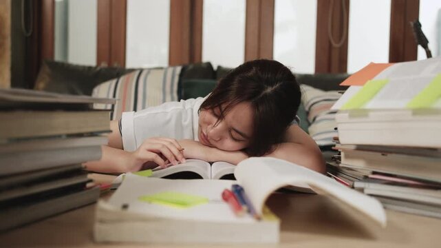 College Asian teenage girl tired and burned out from overwhelmed study pile of books, stressed learning at home with stack of textbooks, reading and writing for school exam, homeschooling education.