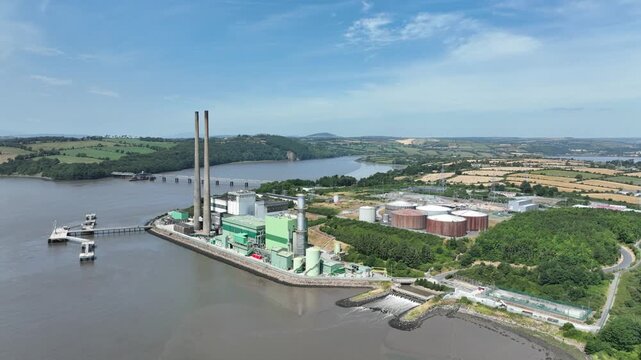 Smooth cinematic drone flight over a riverside electricity power plant in County Wexford with views across the River Suir estuary.