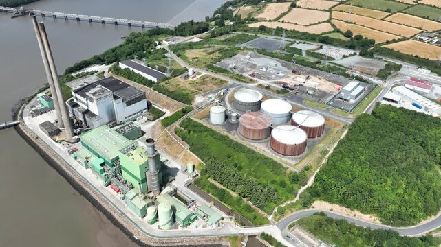 Cinematic aerial footage of a riverside power station along the River Suir in County Wexford, Ireland, with cooling towers, shoreline and surrounding countryside.