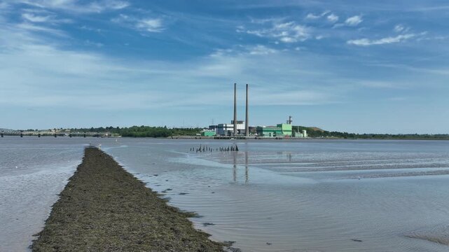 Professional aerial stock footage of an electricity power plant on the River Suir in County Wexford, Ireland, ideal for documentaries, news and energy presentations.