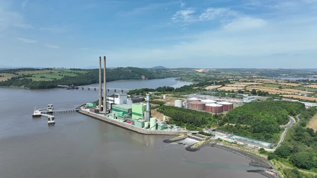 Aerial perspective of a large power station beside the River Suir in Ireland, featuring energy infrastructure against a natural riverside backdrop.