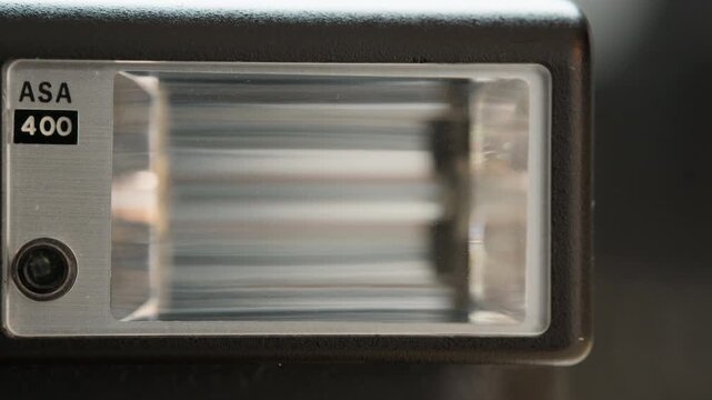 Close-up of a small vintage clip-on camera flash, the xenon flash tube and its fresnel diffuser filling the frame. A detailed look at a piece of retro analog photography gear that once lit every shot.