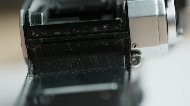 Side close-up of the light seal channel of a vintage 35mm camera being wiped with an alcohol-soaked cloth, degreasing the groove for fresh seals. A prep step of analog restoration &ndash; a clean, sound bas
