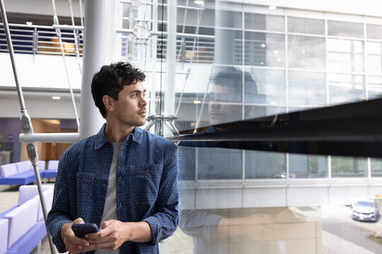 Thoughtful young man in office next to glass window