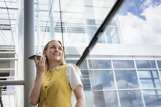 Smiling woman talking on mobile in bright office
