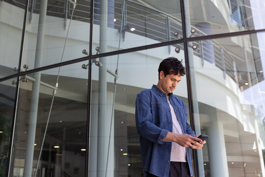 Man using phone near modern glass office
