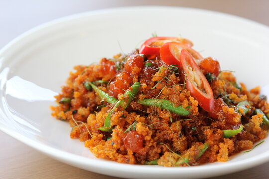 Authentic Thai dish, crispy catfish stir-fried with red chili paste and salted duck egg served on white porcelain plate.