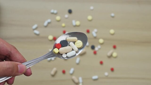 Hand holds metal spoon piled high with colorful pills and tablets, warning about medication overdose risks