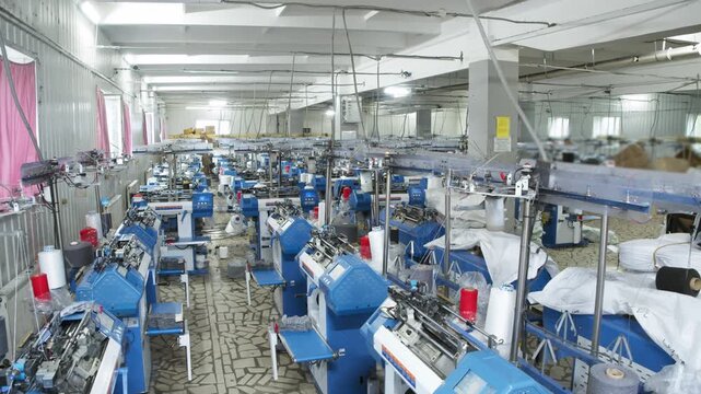 Large textile factory with extensive rows of automated knitting machines operating in spacious production hall