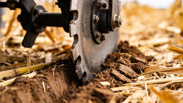 Farm equipment cuts into soil with crop residue present in a field during a farming activity