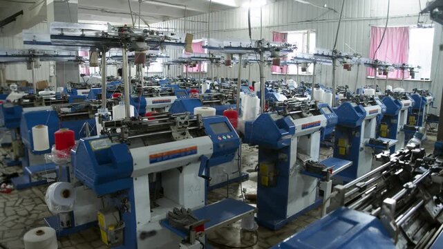Large textile factory filled with rows of automated knitting machines for high volume manufacturing