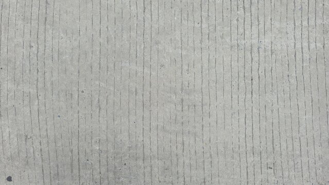Grey broom finished concrete floor texture with parallel lines. Close-up of anti-slip brushed concrete ground, showcasing clean vertical combed lines and fine rustic grain.