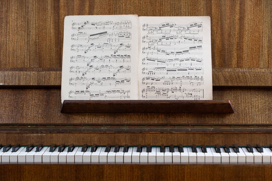 Vintage upright piano with classical sheet music on the music stand, showcasing timeless musical heritage, acoustic instrument, traditional composition and public domain music.