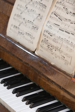 Vintage upright piano with classical sheet music on the music stand, showcasing timeless musical heritage, acoustic instrument, traditional composition and public domain music.