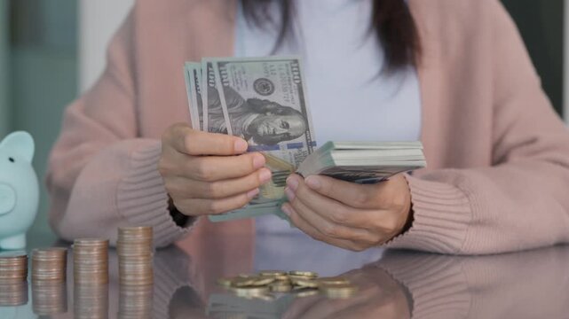 Wealth and financial concept showing woman hands counting US dollar banknotes at desk with coins. Perfect for salary, investment profit, budget, payment and banking marketing media.