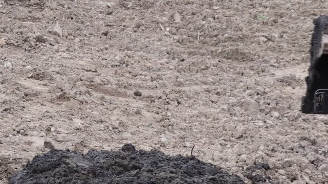 Raw industrial power meets stubborn, saturated soil; thick mud clings to the bucket as the machine wrestles the unyielding terrain