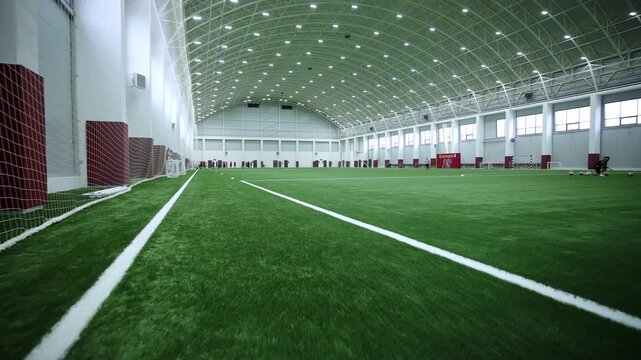 Symmetric arched roof structures rise above silent soccer stadium before match. Organized environment suggests professional team discipline