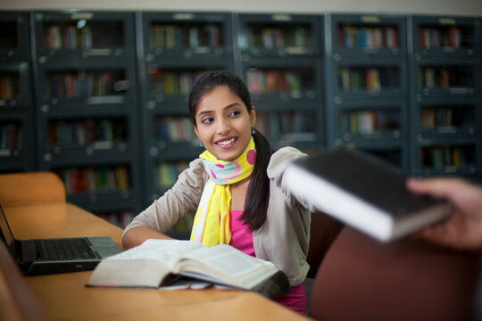 Teenager sitting in library with book