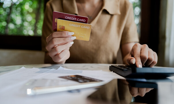 Woman holding credit cards while calculating expenses and reviewing bills, representing credit debt, personal finance, financial stress, and money management.