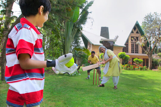 Young boy playing cricket with grandmother