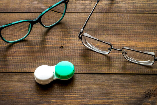 Eye problems. Glasses with transparent lenses and contact lenses on dark wooden background
