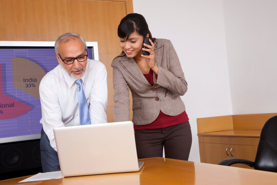 Senior executive and female executive looking at laptop