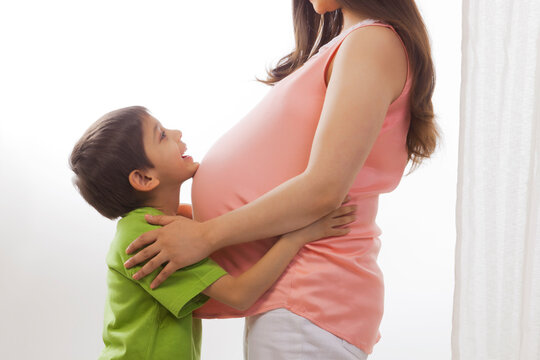 Boy resting chin on belly of pregnant mother