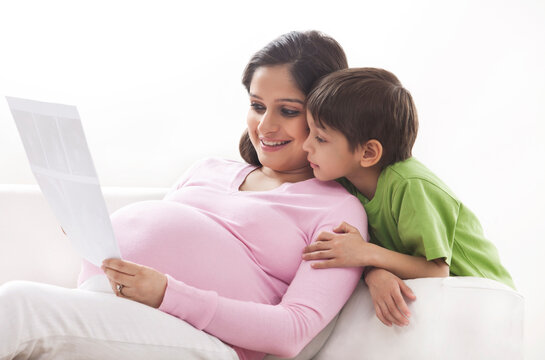 Pregnant mother and son looking at ultrasound scans