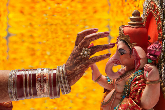 Close-up of a brides hand applying tilak to ganesh idol