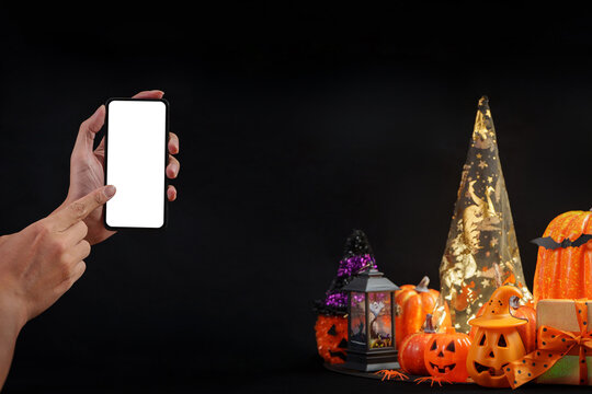 Hand holding smartphone with blank mockup screen for AI technology app during Halloween