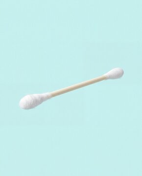 A single white cotton swab with a wooden stick isolated against a soft light blue background studio.