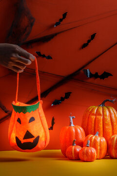 Cropped hand holding pumpkin trick or treat bag for Halloween celebration