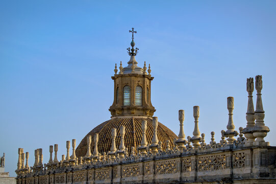 Spanish Renaissance architecture: Tiled dome and ornate lantern of the Royal Chapel at Seville Cathedral framed by stone cresting in Seville, Spain.